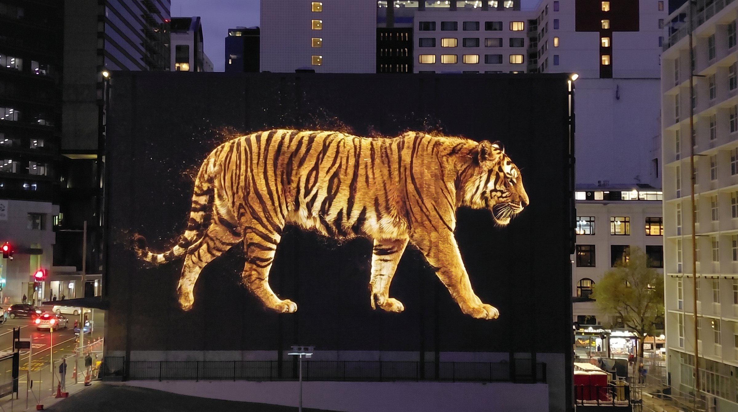 Artist render of a tiger projected across the station facade at dusk